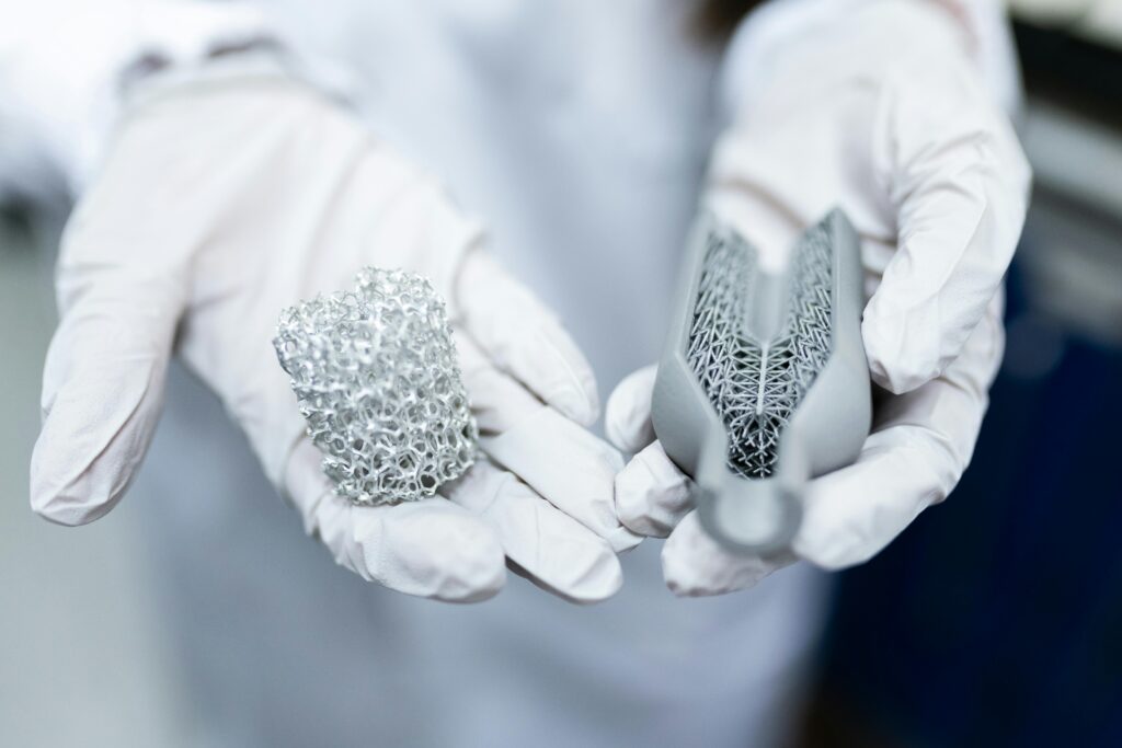 Laboratory setting showing gloved hands holding innovative 3D printed metal structures.